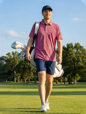 Model in rose flower performance jersey print polo with a golf bag over shoulder outdoors, full-body shot