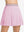 Front lower body shot of model wearing light pink women's moisture-wicking athletic tennis skirts