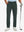 Lightweight moisture wicking dress pants in dark green, front lower-body with model leaning on golf club.