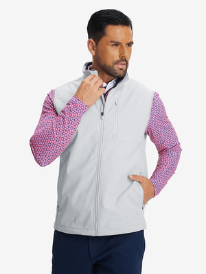 Model front half-body shot with one hand in pocket wearing sleeveless softshell fleece outdoor vests with 6 pockets in light gray