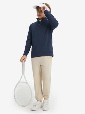 Model wearing a cap and holding a tennis racket, youth winter micro-fleece quarter zip pullover in navy