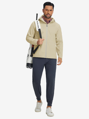 Model with backpack, wearing reflective hooded softshell jacket in light khaki, full-body outdoor look.
