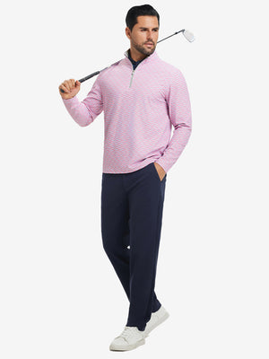 Full-body shot of model holding golf club, dressed in full print quarter zip pullover in pink small fish.