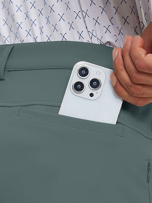 Close detail of hand placing phone into back pocket of lightweight moisture wicking dress pants in dark dusty blue.