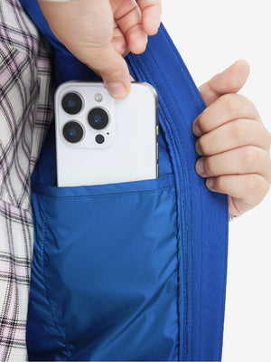Close-up of boys full-zip fleece-lined puffer vest pocket holding a phone, practical detail in klein blue