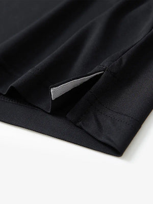 Detail view of the black long sleeve pique polo, showcasing the hem opening and refined design.