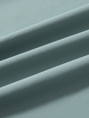 Close-up of beryl green ventilated pique performance polo fabric texture.