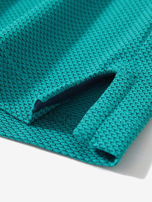 Detail of the side vent hem on the turquoise feather weight jacquard polo shirts, showing the split design feature