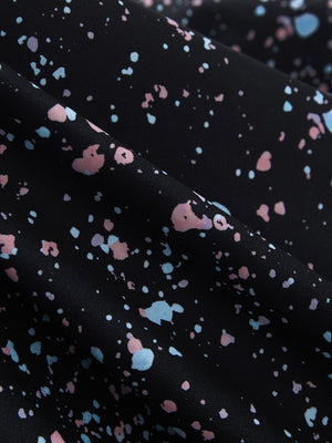 Close-up of black splatter stretch printed collarless henley golf shirts, showcasing texture and print details.