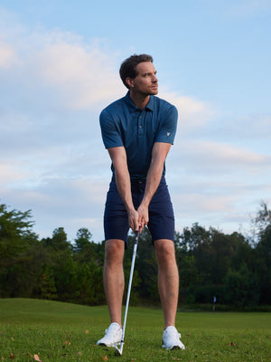 Model in navy blue your favorite jacquard polo preparing to tee off, full-body shot