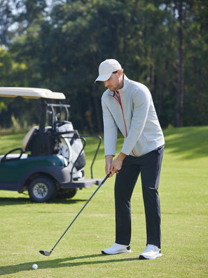 Model in light grey softshell water resistant lightweight jacket preparing to tee off, full-body shot