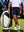 Outdoor shot of a model's lower body holding a golf club, wearing the navy 4-way stretch performance solid shorts with a relaxed fit
