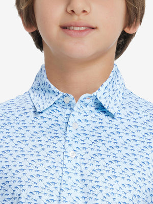 Front view of youth wearing blue dinosaur performance print boys golf polo, showing collar and chest fit