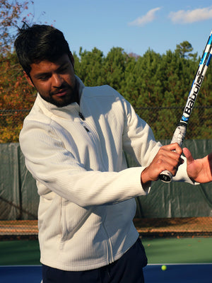 A model wearing a beige textured insulated winter jacket is playing tennis