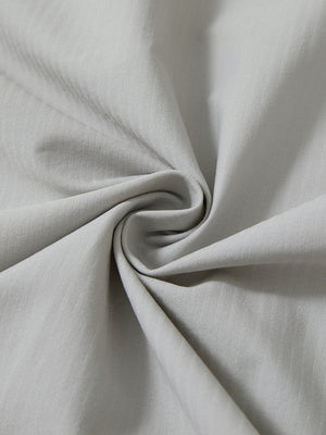 Close-up fabric detail of lightweight water-resistant outerwear jacket, smooth silver grey texture