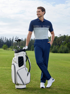Model in blue indigo water resistant everyday pants standing with a golf bag outdoors, full-body shot
